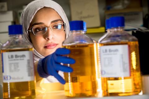 Image of female scientist grabbing bottled chemicals