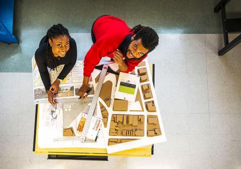 Image of architect students standing over their drafting materials