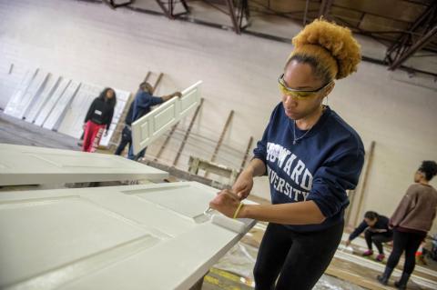 Howard University Student painting door with a paint roller